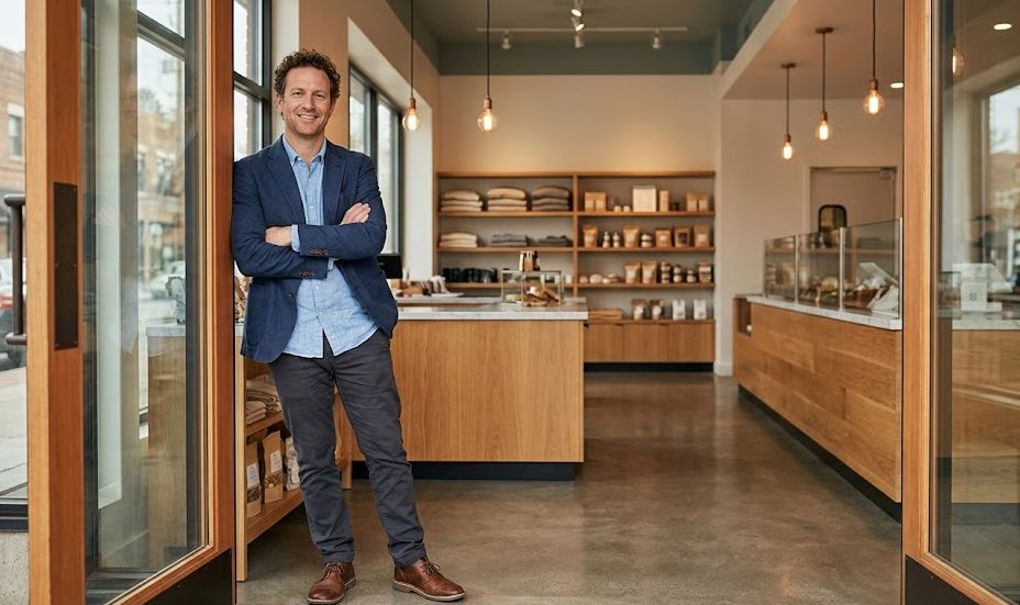Confident franchise owner standing inside the entrance of their modern retail business location with clean commercial interior visible