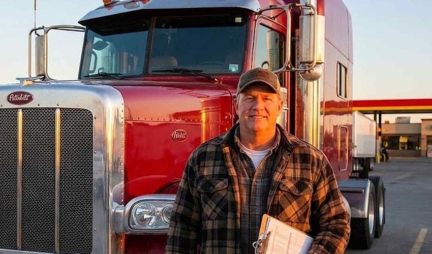 Trucking owner-operator with semi truck reviewing business documents.